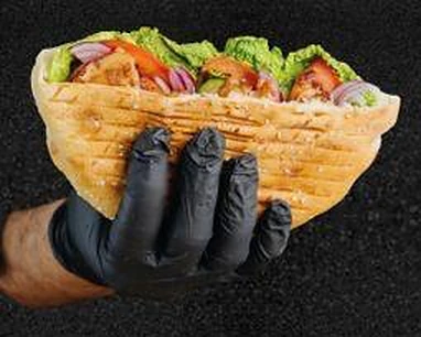 Döner im gegrillten Fladenbrot mit Salat, Tomate und Zwiebeln, in der Hand gehalten